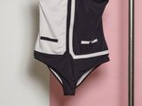 black and white swimsuit hanging on a clothes rack against a pink and white wall