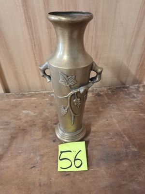un vase en argent posé sur un plancher en bois, avec une étiquette de prix devant