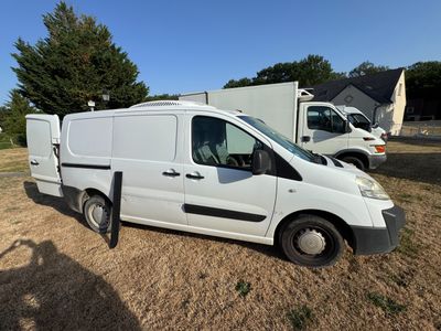 une camionnette blanche garée dans un champ avec d'autres véhicules