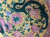 a yellow plate with a dragon and flowers on it