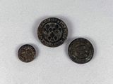 three ancient coins are shown on a white surface