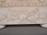 a white marble box with flowers and leaves on it