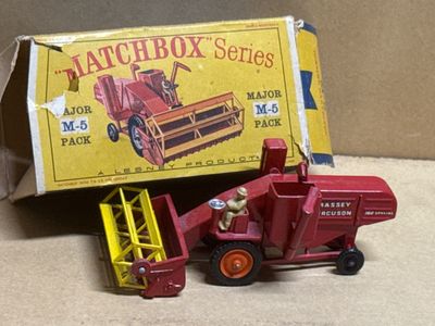 a red toy truck and a red tractor in front of a matchbox box