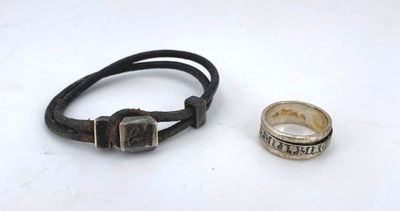 pair of silver and leather bracelets and a ring on a white surface