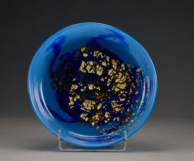 un bol bleu contenant des paillettes dorées, posé sur un socle