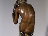 bronze statue of a man sitting on top of a glass pedestal