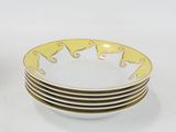 four yellow and white plates stacked on top of each other on a white surface