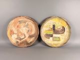 two ceramic bowls with designs on them sitting side by side