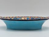 blue bowl with multicolored flowers on it on a white surface