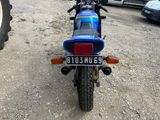 a motorcycle that is parked in a lot with a tractor behind it