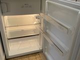 an open refrigerator in a small kitchen with tile flooring