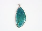a close up of a blue stone pendant on a white surface