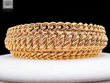 un gros plan d'un bracelet en or posé sur une assiette blanche