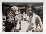 a black and white photo of an old man and a naked man