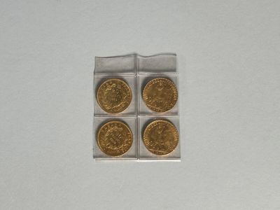 quatre pièces d'or se trouvent dans une boîte en plastique transparent posée sur une surface blanche