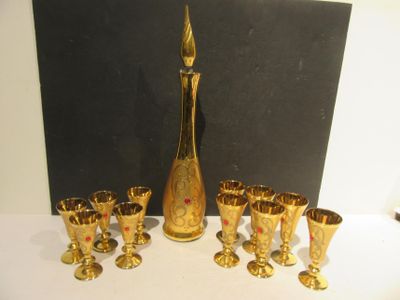 a lot of gold wine glasses and a gold decanter