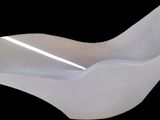 une chaise blanche à l'assise incurvée sur fond noir