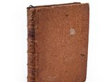 an old book with a brown cover sitting on top of a white surface
