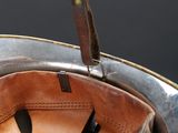 a brown leather bag with a leather handle on a silver plate