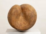 a wooden sculpture on a white pedestal with a white background
