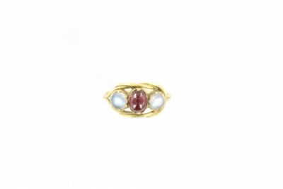 un gros plan d'une bague en or sertie d'une pierre rouge et blanche