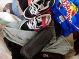 a pile of clothes and a bag of snacks on a bed