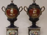 pair of antique vases with painted faces on them on a white background