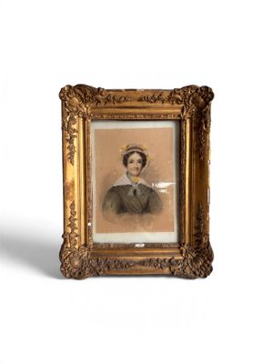 une vieille photo d'une femme portant un chapeau et une robe, dans un cadre doré