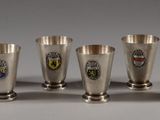 six silver cups with crest emblems are lined up on a table