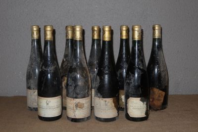 Six bouteilles de vin sont alignées sur une table devant un mur.