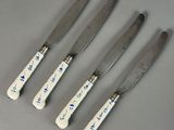 four knives with blue and white designs on them sitting next to each other