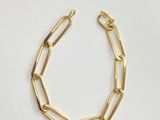 a gold chain bracelet with a link on a white background