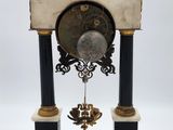 a clock that is sitting on a stand on a white surface