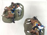 three figurines of horses and riders in a display case