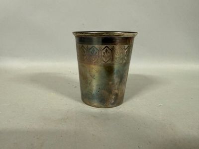 une coupe en argent posée sur une surface blanche