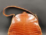 un sac à main en cuir de crocodile orange sur fond gris