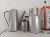 a silver pitcher and a silver tea pot on a shelf