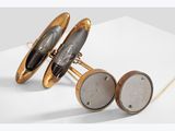 pair of gold and silver cufflinks on a white surface