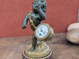 a small statue of a boy with a clock on a table