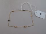 gold plated ankle chain with black beads and a white tag
