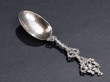 an antique silver spoon on a black surface with a black background
