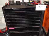 une armoire à outils noire, sur laquelle sont posés des outils, dans un garage