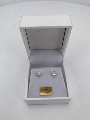 a pair of earrings in a box on a white surface
