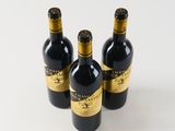 three bottles of wine sitting next to each other on a white surface