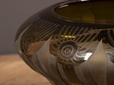 a silver vase sitting on a table with a wooden surface