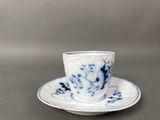 a blue and white cup and saucer sitting on a table