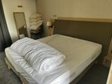 un lit sur lequel sont posés une couette blanche et des oreillers
