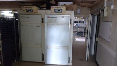 several refrigerators and freezers are lined up in a room