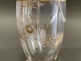 a glass vase that has a gold decoration on it