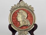 an image of a gold and red medallion with a woman ' s head